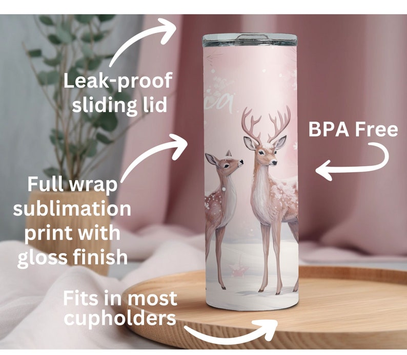 May include: A pink stainless steel tumbler with a full wrap sublimation print of two deer in a snowy forest. The tumbler has a leak-proof sliding lid and fits in most cupholders. It is BPA free.