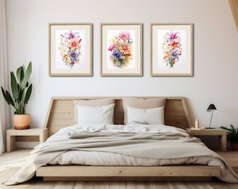 Puede incluir: Tres acuarelas enmarcadas de ramos de flores coloridos, expuestas en una pared blanca sobre un cabecero de cama de madera.