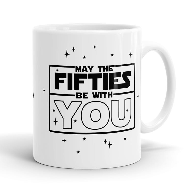 May include: White ceramic coffee mug with a black graphic that reads "May the Fifties Be With You" surrounded by small stars.