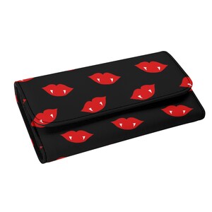 May include: Black wallet with a repeating pattern of red vampire lips. The wallet has a flap closure and is made of a textured material. The design is a bold and eye-catching accessory.