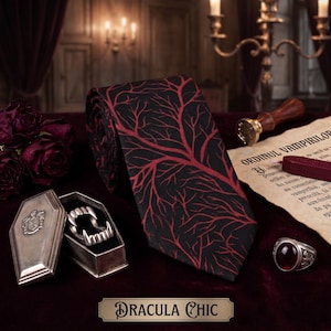 May include: A black necktie featuring a red branching tree pattern, accompanied by a silver coffin-shaped box containing vampire fangs, a silver ring with a red stone, a wax seal stamp, and a parchment document titled ORDINUL VAMPIRILOR.