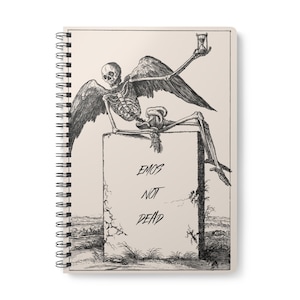 May include: Spiral-bound notebook featuring a monochrome illustration of a winged skeleton holding an hourglass. The skeleton sits on a tombstone inscribed with "EMOS NOT DEAD". The notebook has a cream-coloured cover.