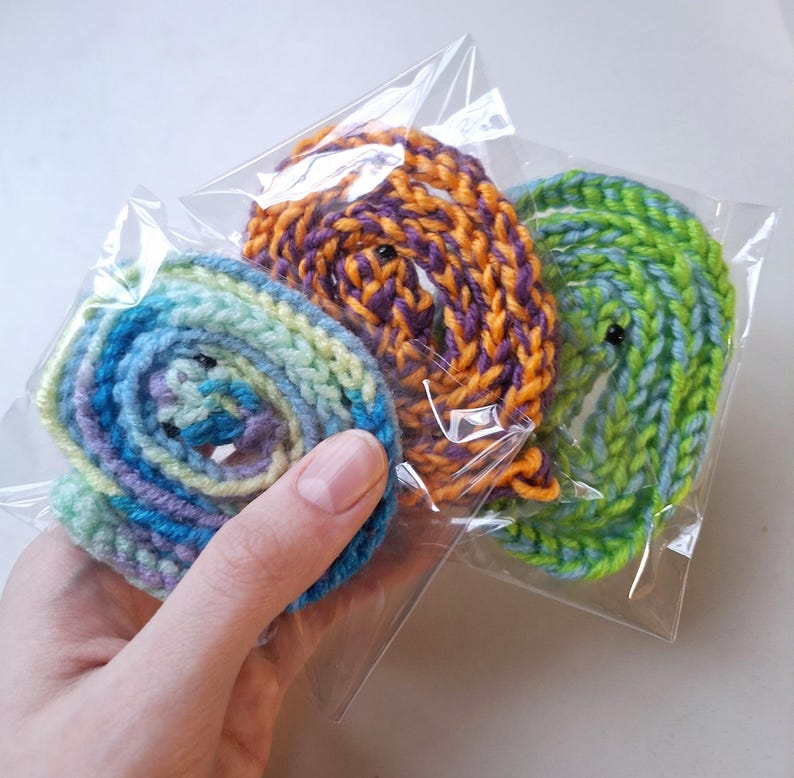 May include: Three skeins of yarn in plastic bags. One skein is a light blue and green ombre, one is a purple and orange ombre, and one is a bright green.