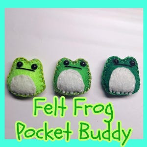 May include: Three felt frog pocket buddies in shades of green with white bellies and black eyes. The frogs are handmade with a stitched border. Text on the image reads "Felt Frog Pocket Buddy".