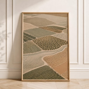 May include: A vertical rectangular framed wall art print featuring an aerial view of agricultural fields in shades of beige, tan, olive green, and sage. The landscape displays various textures of crops, rows of trees, and winding dirt paths.