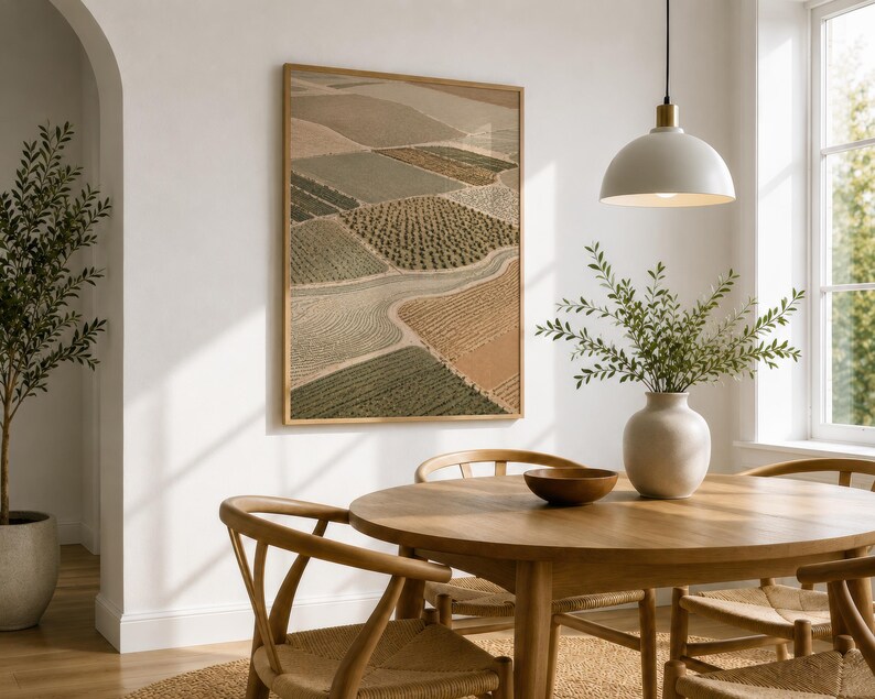 Pode incluir: Uma impress&atilde;o de arte de parede vertical emoldurada com uma vista a&eacute;rea de campos agr&iacute;colas em tons de bege, verde-oliva e castanho. A obra exibe um mosaico de linhas de cultivo texturizadas e caminhos sinuosos, numa moldura de madeira clara.