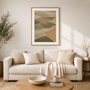 Pode incluir: Uma impress&atilde;o de arte de parede emoldurada com uma vista a&eacute;rea de campos agr&iacute;colas em tons de verde, bege e castanho. A impress&atilde;o retangular &eacute; exibida numa moldura de madeira clara, mostrando uma paisagem em mosaico.