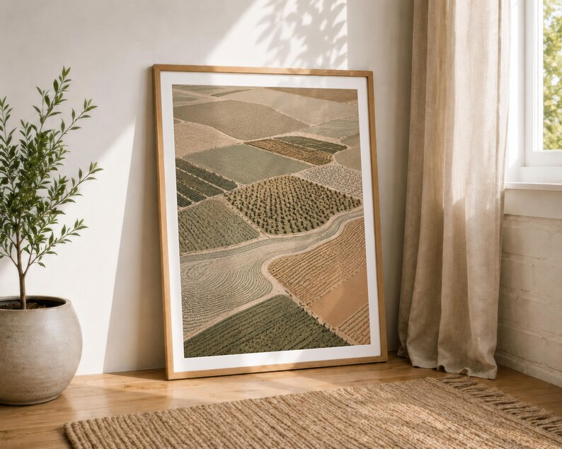 Pode incluir: Uma impress&atilde;o de arte de parede vertical emoldurada apresentando uma vista a&eacute;rea de campos agr&iacute;colas em tons de bege, castanho, verde-azeitona e s&aacute;lvia. A paisagem exibe v&aacute;rias texturas de culturas e padr&otilde;es de solo separados por caminhos.