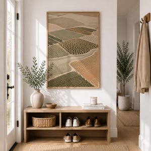 Pode incluir: Uma impress&atilde;o de arte de parede retangular com uma vista a&eacute;rea de campos agr&iacute;colas em tons de verde, bege e castanho, inserida numa moldura de madeira clara. A obra de arte exibe uma paisagem em mosaico com filas de culturas.