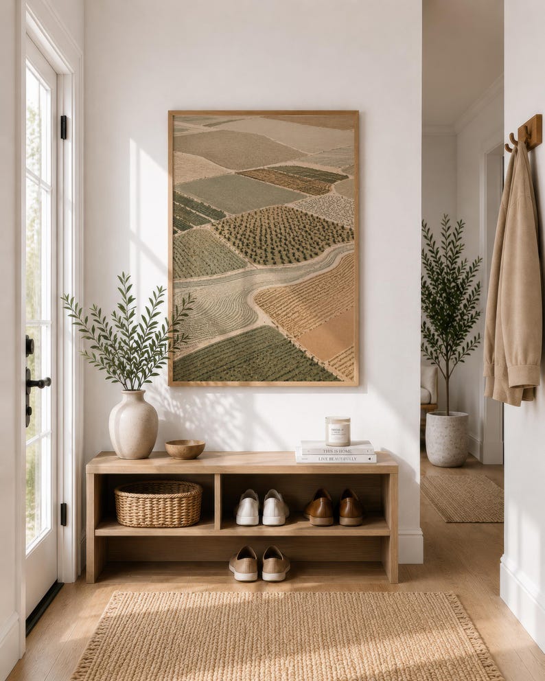 Pode incluir: Uma impress&atilde;o de arte de parede retangular com uma vista a&eacute;rea de campos agr&iacute;colas em tons de verde, bege e castanho, inserida numa moldura de madeira clara. A obra de arte exibe uma paisagem em mosaico com filas de culturas.