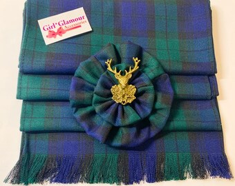 May include: A green and blue plaid kilt sash with a gold stag pin and a matching green and blue plaid bow. The sash has a fringe on the bottom.
