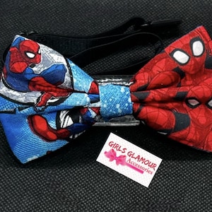 Peut inclure: Un nœud papillon bleu et rouge avec un motif Spiderman. Le nœud papillon a une sangle réglable et est fait de tissu. Le nœud papillon est sur un fond noir. L'étiquette indique "Girls Glamour Accessories".