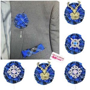 Puede incluir: Un conjunto de cinco boutonnières de tela tartán azul y negro con diferentes acentos decorativos. Los acentos incluyen un ciervo, un nudo celta con un strass azul y un copo de nieve plateado con un strass rosa. Las boutonnières están sujetas a un alfiler.