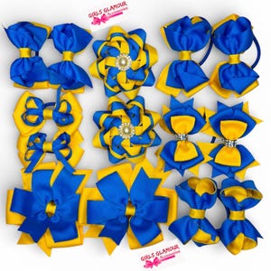 Puede incluir: Colección de lazos para el pelo azules y amarillos en varios estilos. Algunos lazos presentan una decoración central. Los lazos están hechos de cinta y están dispuestos sobre una superficie blanca. El texto "GIRLS GLAMOUR Accessories" es visible.