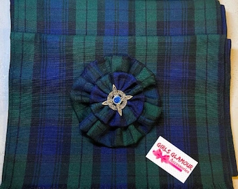 May include: A green, blue, and black plaid fabric sash with a fringed edge. A blue and green fabric flower with a silver pin is attached to the sash. The text "Girls Glamour Accessories" is printed on a white tag.