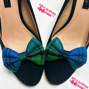 May include: A pair of black shoes with a green and blue plaid bow on each shoe. The shoes are on a white background. The text "Girls Glamour Accessories" is visible in the image.