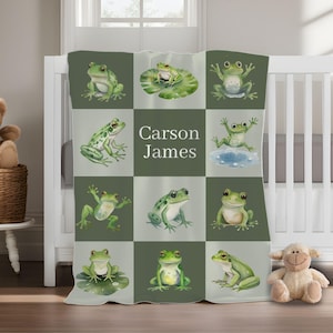 May include: A green and white baby blanket featuring a grid pattern with watercolor illustrations of frogs. The blanket has the name "Carson James" printed in the center. The frogs are in various poses, some on lily pads.