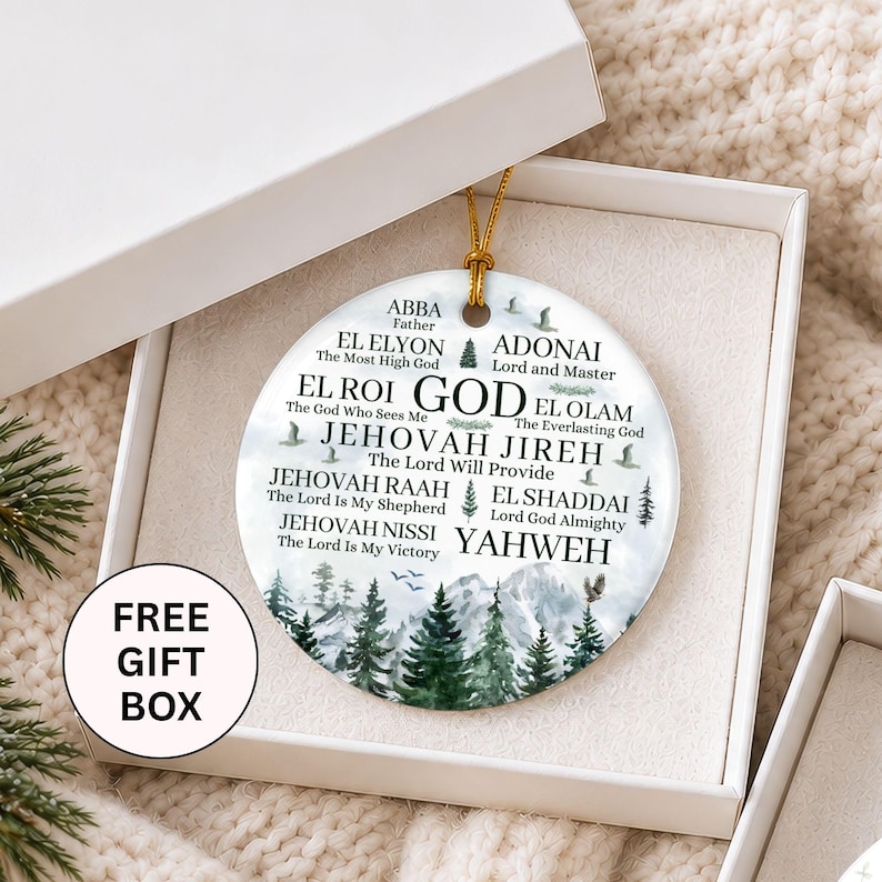 May include: A round white ceramic ornament featuring a mountain and pine tree landscape with printed text including ABBA, EL ELYON, ADONAI, EL ROI, EL OLAM, JEHOVAH JIREH, JEHOVAH RAAH, EL SHADDAI, JEHOVAH NISSI, and YAHWEH, suspended by a gold string in a white box.