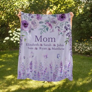 May include: A lavender-colored blanket with floral and butterfly designs. The word "Mom" is centered, with names below. The blanket features purple roses, lavender sprigs, and butterflies, creating a soft, feminine aesthetic.