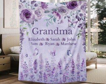 May include: A lavender-colored blanket with the word "Grandma" in large letters. The blanket features floral and butterfly designs in shades of purple. Names are listed below "Grandma".