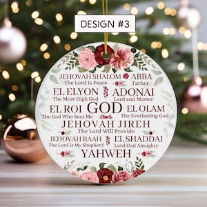 May include: A round white ceramic ornament featuring a floral border of pink and dark red roses. The text includes DESIGN #3, GOD, and various names for God such as JEHOVAH SHALOM, ABBA, EL ELYON, ADONAI, EL ROI, EL OLAM, JEHOVAH JIREH, JEHOVAH RAAH, EL SHADDAI, and YAHWEH.