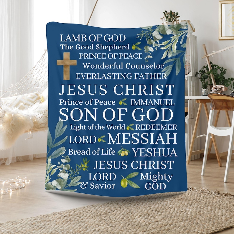 May include: A blue throw blanket with a white floral design and white text. The text reads: 'LAMB OF GOD', 'The Good Shepherd', 'PRINCE OF PEACE', 'Wonderful Counselor', 'EVERLASTING FATHER', 'JESUS CHRIST', 'Prince of Peace', 'IMMANUEL', 'SON OF GOD', 'Light of the World', 'REDEEMER', 'LORD', 'MESSIAH', 'Bread of Life', 'YESHUA', 'JESUS CHRIST', 'LORD', 'Mighty', '& Savior', 'GOD'.