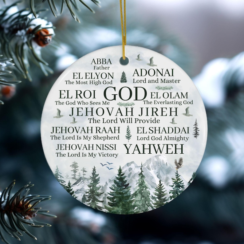 May include: A round white ceramic ornament featuring a gold hanging string. The surface displays black text listing various names of God, including Abba, El Elyon, Adonai, El Roi, El Olam, Jehovah Jireh, Jehovah Raah, El Shaddai, Jehovah Nissi, and Yahweh.