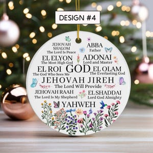 May include: A round white ceramic ornament featuring the text DESIGN #4 at the top. The surface displays various names of God in black lettering, including Jehovah Shalom, El Roi, and Yahweh, surrounded by colorful floral illustrations and butterflies.