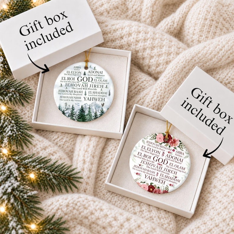May include: Two round white ceramic ornaments in open gift boxes. One ornament features a green pine forest graphic, the other a floral design. Both display the text GOD and various names like JEHOVAH JIREH, EL SHADDAI, and YAHWEH with meanings.