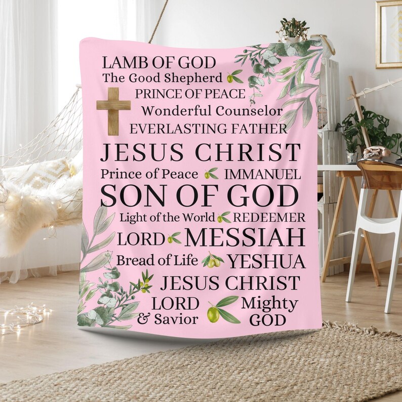 May include: Pink tapestry with a white cross and text that reads "Lamb of God", "The Good Shepherd", "Prince of Peace", "Wonderful Counselor", "Everlasting Father", "Jesus Christ", "Prince of Peace", "Immanuel", "Son of God", "Light of the World", "Redeemer", "Lord", "Messiah", "Bread of Life", "Yeshua", "Jesus Christ", "Lord", "& Savior", "Mighty", "God".
