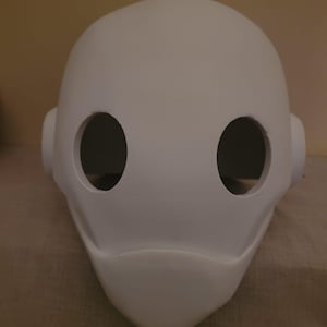 May include: White plastic mask with two eye holes. The mask has a rounded top and a pointed chin.
