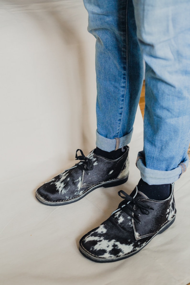 Puede incluir: Un par de zapatos de cordones de cuero de vaca blanco y negro con suela de goma negra.