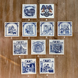 May include: A collection of ten square ceramic tiles featuring blue and white illustrations of historical scenes, each labeled with a letter from A to K. The designs depict various indoor settings, figures in period clothing, and ornate decorative borders.