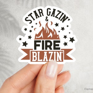 May include: White sticker with black text that reads "Star Gazin' & Fire Blazin'" with a brown flame graphic and black stars around the text.