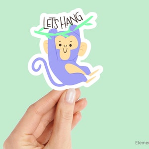 May include: A purple monkey with a yellow face and a green vine hanging from its hand. The monkey is holding onto the vine with its other hand. The vine has the text "Let's Hang" written on it.