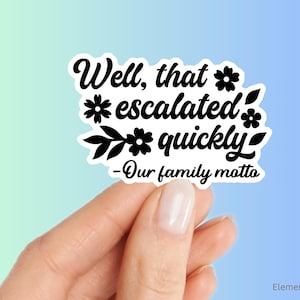 May include: White sticker with black text and floral accents that reads "Well, that escalated quickly - Our family motto".
