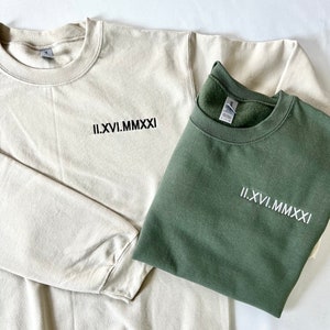 May include: Two sweatshirts, one beige and one green, with the Roman numeral date "II.XVI.MMXXI" embroidered on the front.