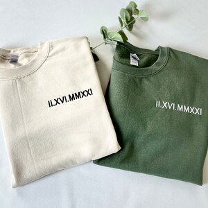 May include: Two sweatshirts, one beige and one green, with the Roman numeral date "II.XVI.MMXXI" embroidered on the front.