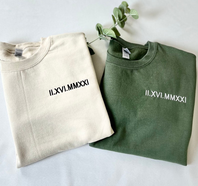 May include: Two sweatshirts, one beige and one green, with the Roman numeral date "II.XVI.MMXXI" embroidered on the front.