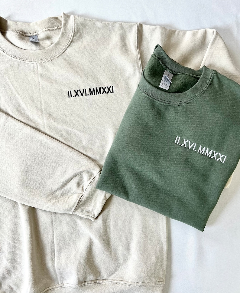 May include: Two sweatshirts, one beige and one green, with the Roman numeral date "II.XVI.MMXXI" embroidered on the front.