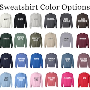 May include: A chart showing 24 different sweatshirt color options. The colors are displayed in a grid of four rows and six columns. Each color is represented by a folded sweatshirt with the color name printed in white text on the front.