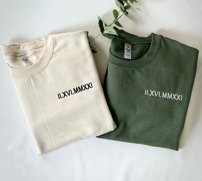 May include: Two sweatshirts, one beige and one green, with the Roman numeral date "II.XVI.MMXXI" embroidered on the front.