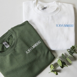 May include: Two sweatshirts, one green and one white, with the same embroidered text in Roman numerals: "II.XVI.MMXXI".