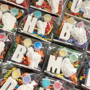 Op de afbeelding: Een set om zelf te beschilderen dierlijke alfabetletters met verfpotjes en kleurrijk papierstrooisel. De letters zitten in een doorzichtige plastic zak.