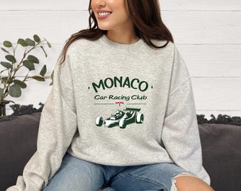 May include: A gray sweatshirt with the text 'MONACO' Car Racing Club and a black and white illustration of a race car.