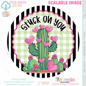 May include: A round design featuring a cactus adorned with pink hearts and flowers, with the text "Stuck on You." The design is set against a green and white checkered background, framed by black and white stripes. The diameter is 12 inches.