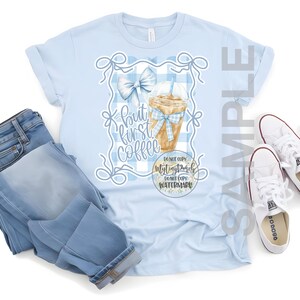 K&ouml;nnte beinhalten: Ein hellblaues T-Shirt mit einem Aquarell-Design eines Eiskaffees mit einer blauen Schleife. Der Text auf dem Shirt lautet "But first coffee" und "Don't copy my designs, don't copy my watermark".