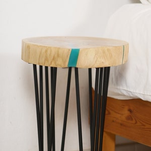 May include: A small wooden side table with a light wood top and a teal blue epoxy resin inlay. The table has black hairpin legs.