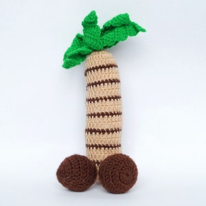May include: A crocheted palm tree toy with a brown and beige striped trunk and two brown coconut-shaped balls at the base.