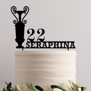 Pode incluir: Topo de bolo preto com um design de vaso, o número 22 e o nome "SERAPHINA".
